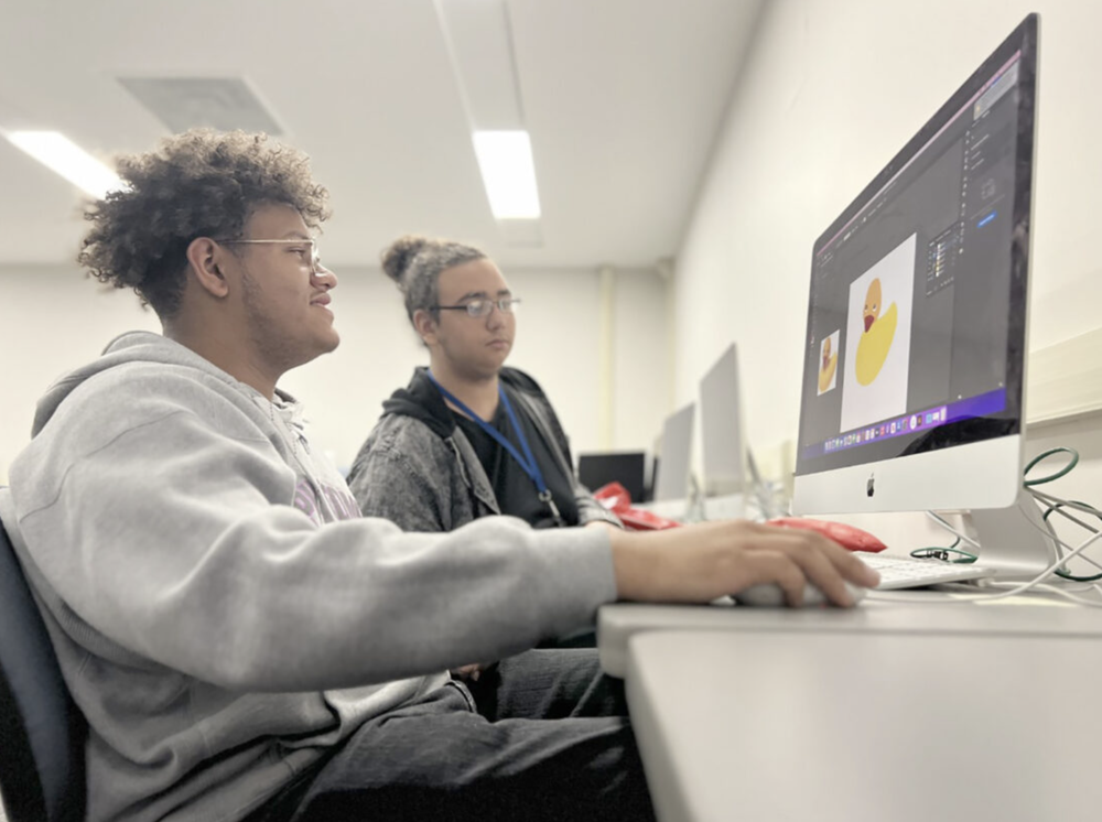 Two young men sitting by a computer 